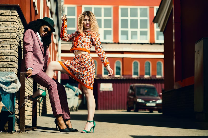 Before image of two women posing in front of a building with a parked car in the background.