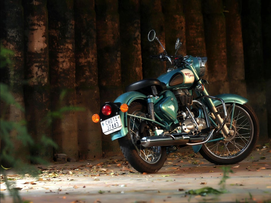Before: Photo of green motorcycle resting by wooden fence