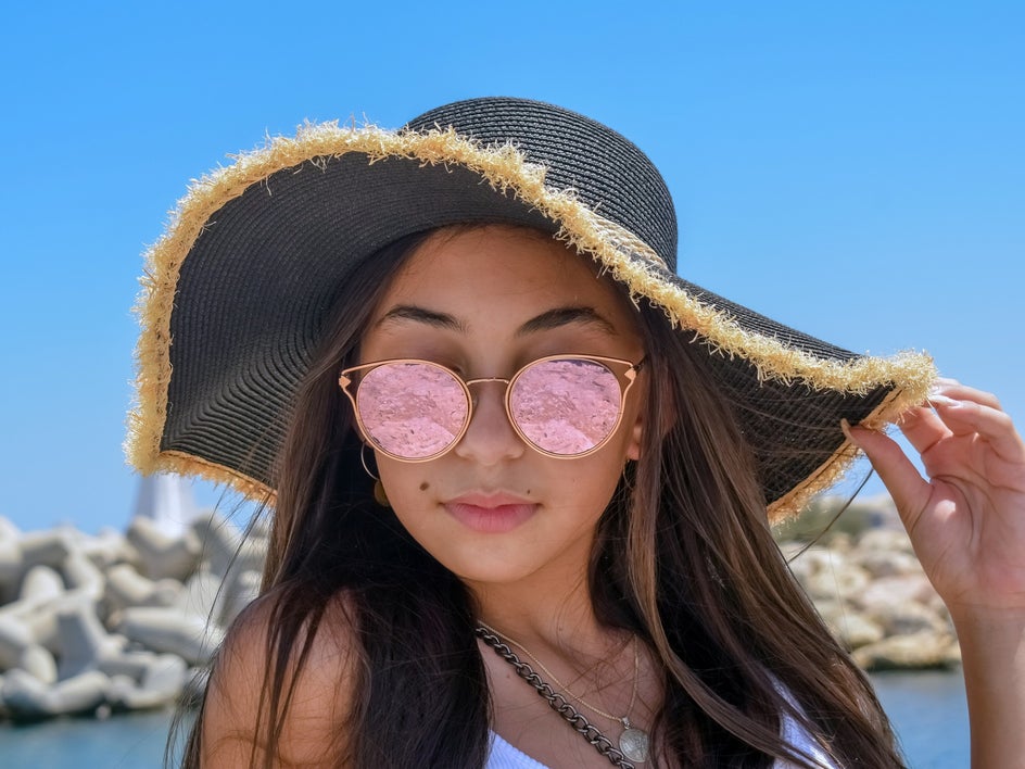 Before: Close up of woman at beach with hat and pink tinted sunglasses